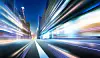 Blurred light trails on a city street between tall buildings at night